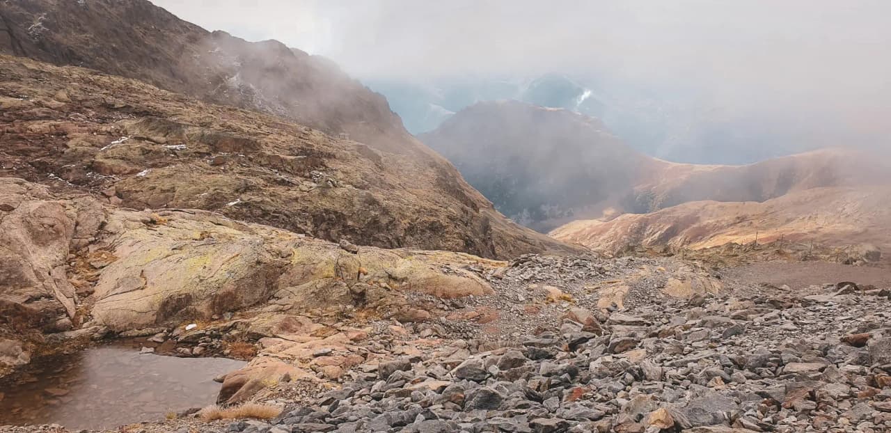Un paysage de montagne impressionnant avec des rochers colorés, des vallées profondes et un ciel brumeux.