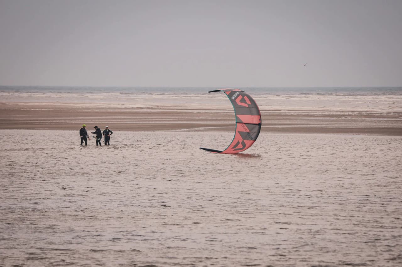 Three kitesurfers at the water's edge, preparing for their adventure on the coast of Zeeland.