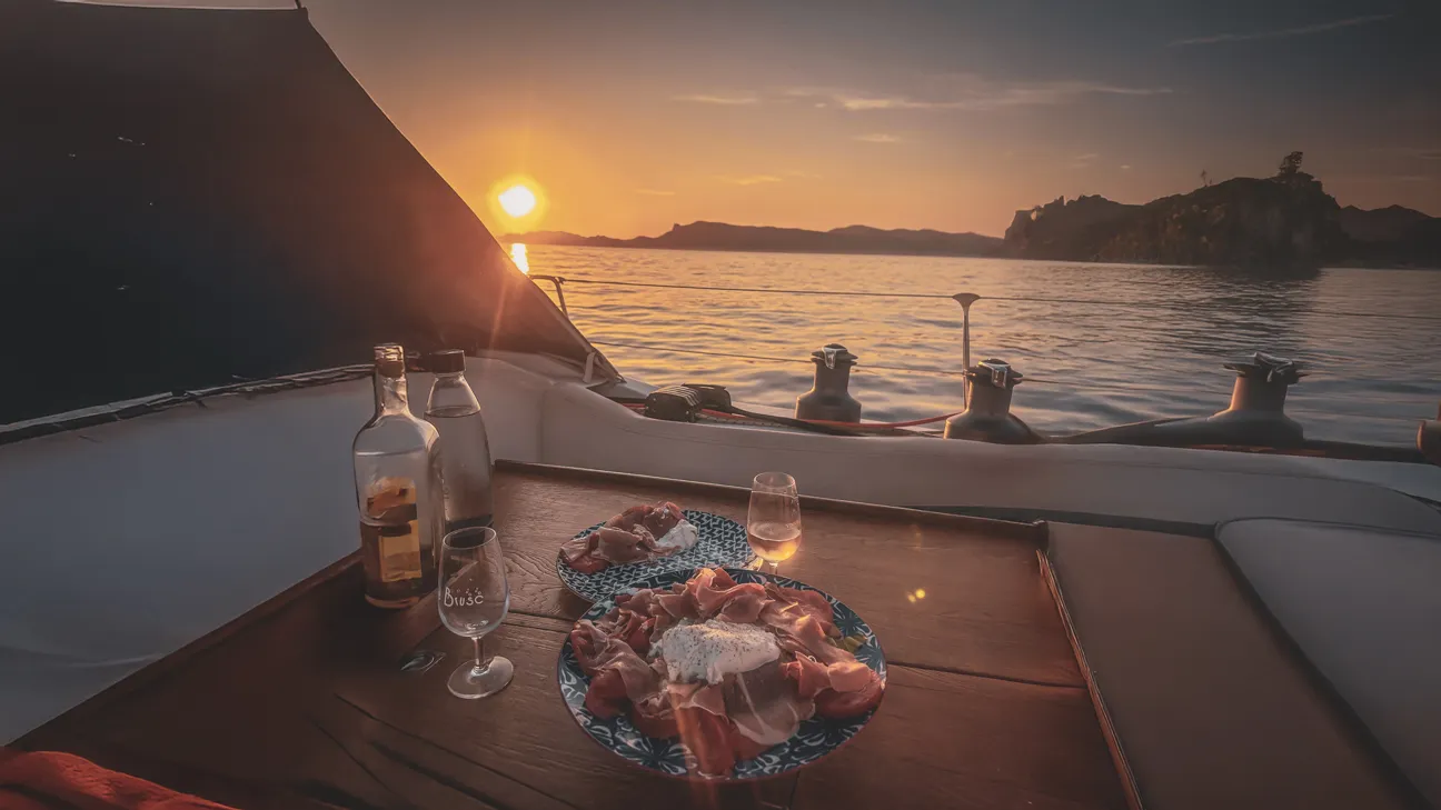 Dîner de plage au coucher de soleil, avec des mets savoureux et une vue sur la mer calme.