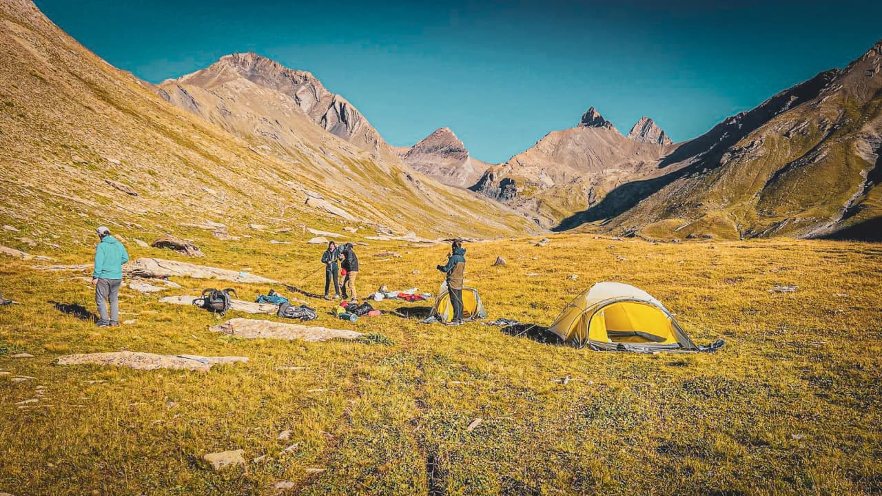 Un groupe de randonneurs installe des tentes sous les majestueuses Aiguilles d'Arves.