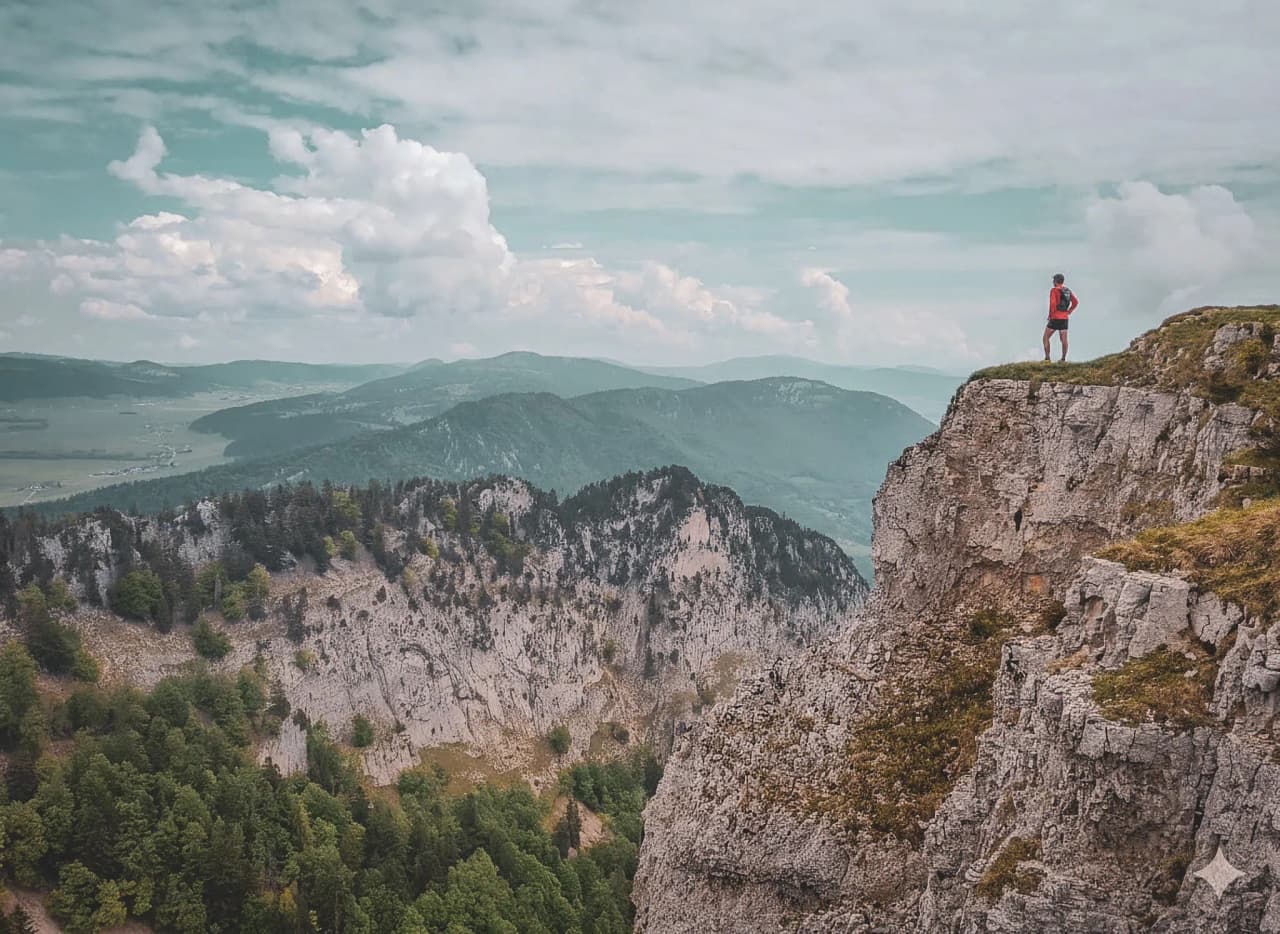 Een avonturier staat op de top van een klif en bewondert het adembenemende berglandschap.