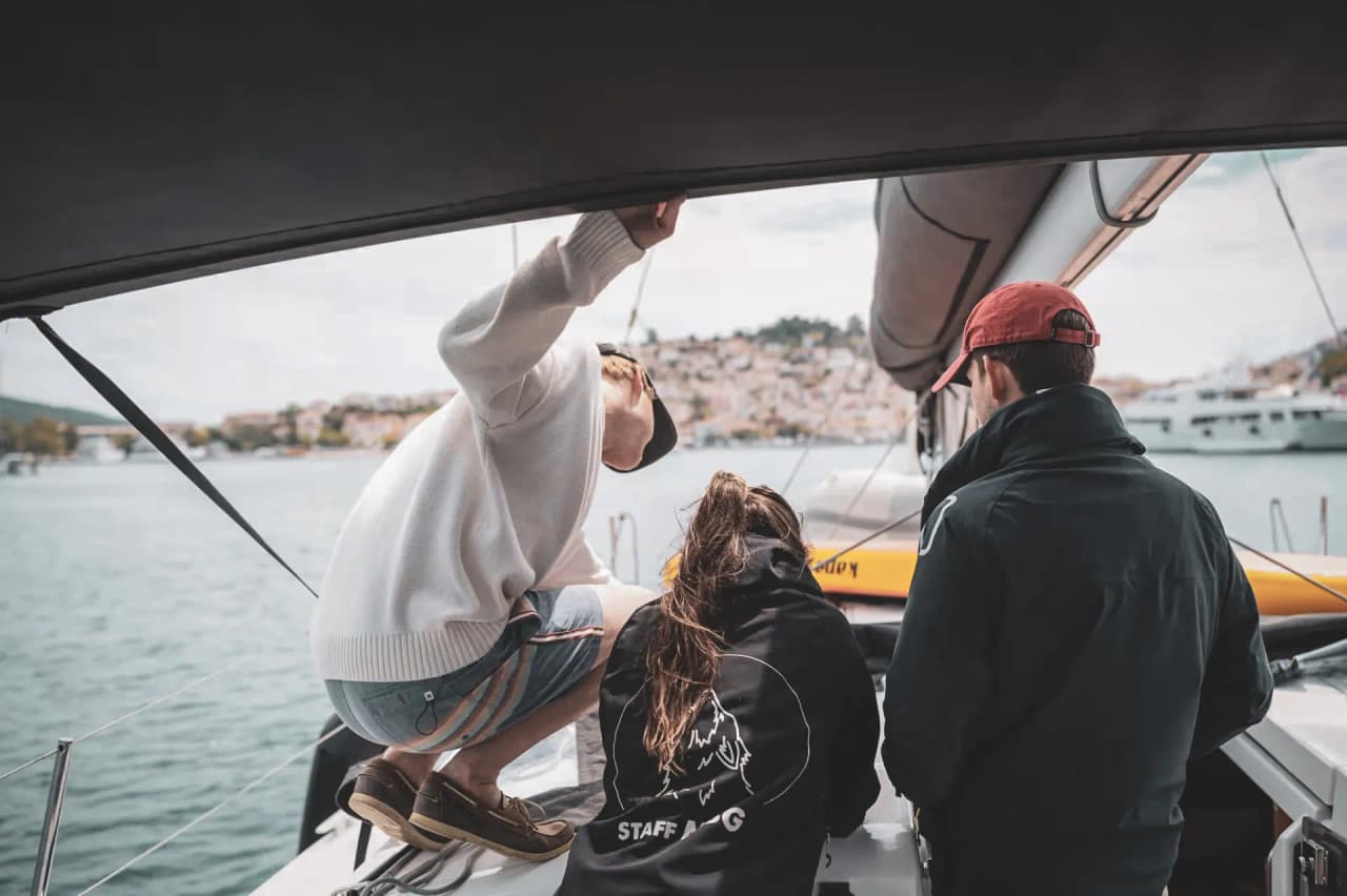 Un groupe de jeunes navigue sur un voilier, découvrant les paysages méditerranéens.