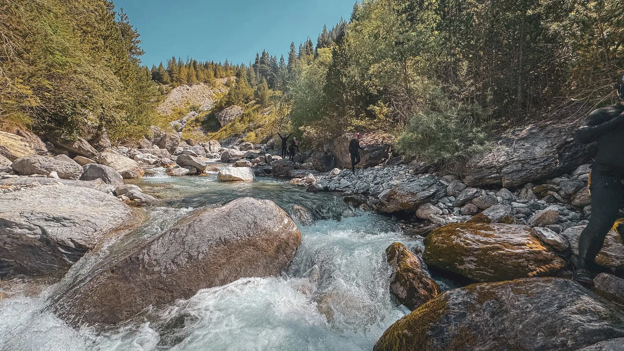 A crystal-clear stream meanders between majestic rocks in the heart of the Alps.
