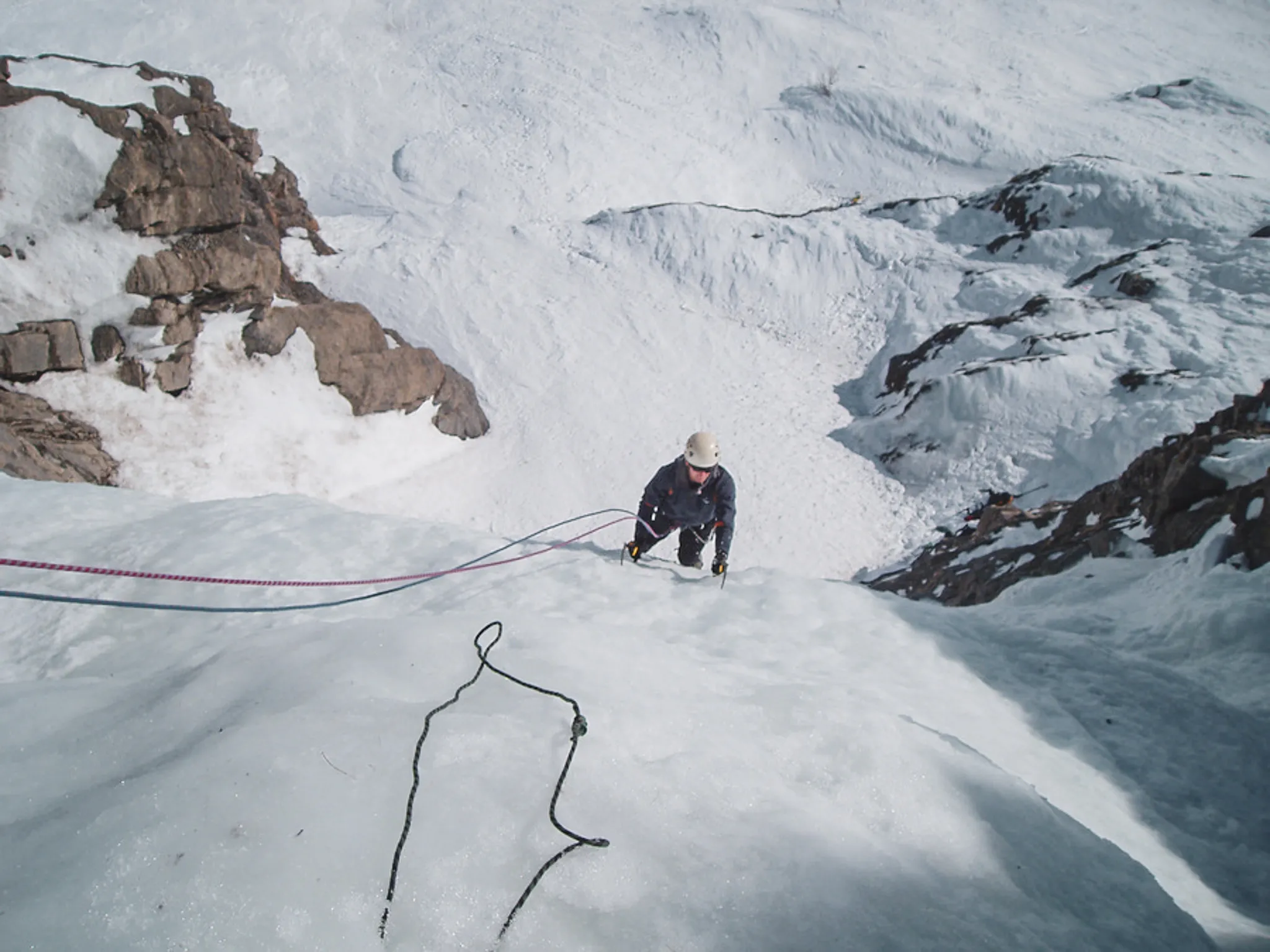 Een klimmer waagt zich op een ijzige wand in een spectaculair Alpenlandschap.
