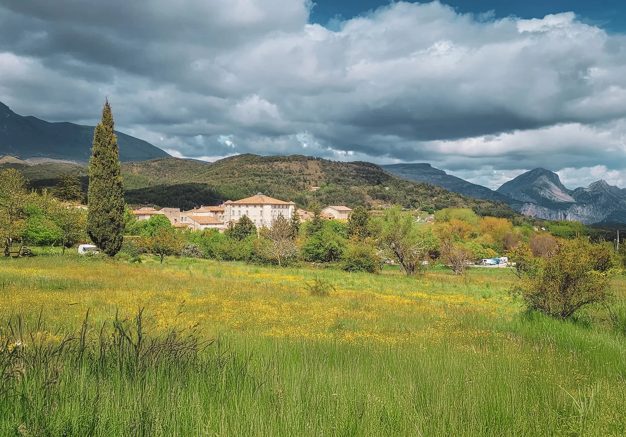 A green landscape with steep hills and majestic clouds, ideal for adventure.