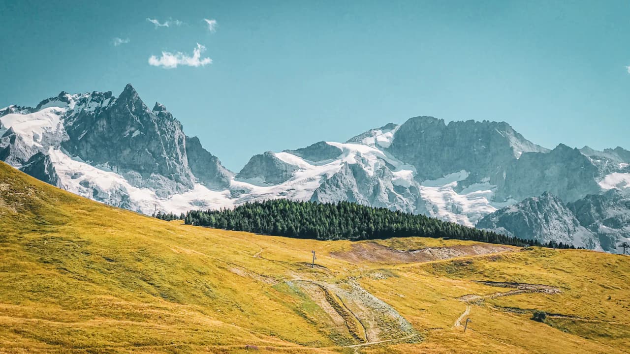 Paysage alpin spectaculaire avec des montagnes majestueuses et des prairies verdoyantes, invitant à l'aventure.