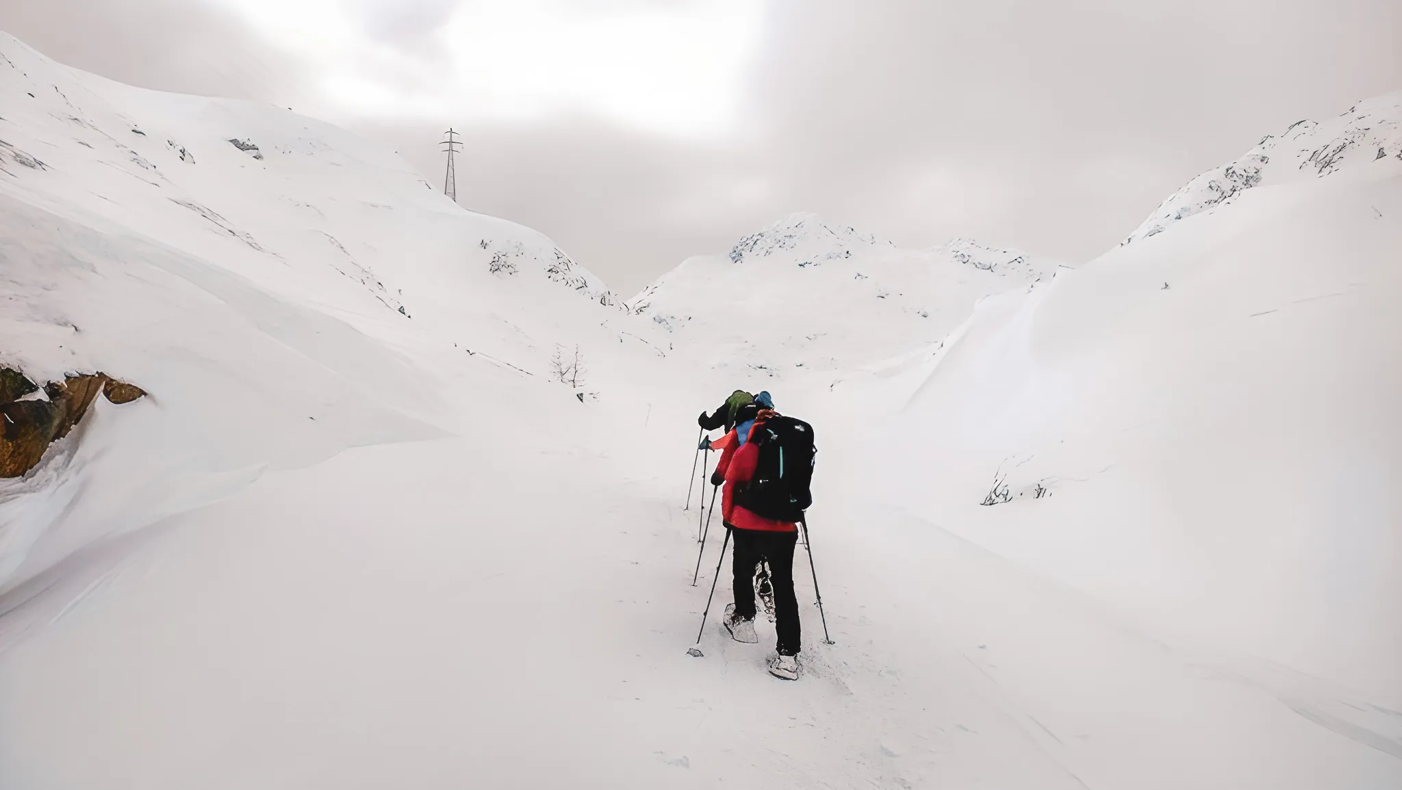 Een groep sneeuwschoenwandelaars baant zich een weg over de besneeuwde vlakte van de Grote Sint-Bernardpas.