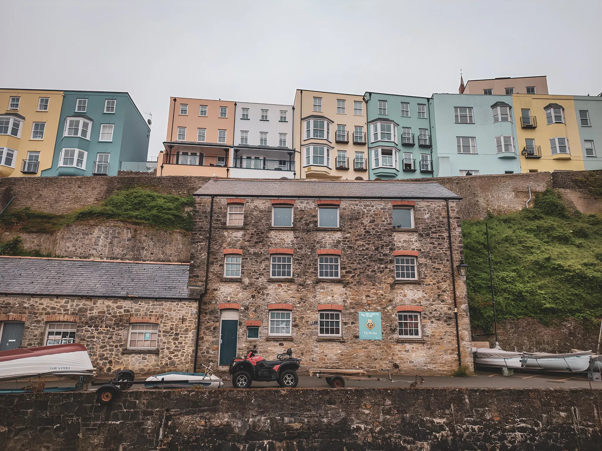 Maisons colorées surplombant le port, évoquant l'aventure en bord de mer gallois.