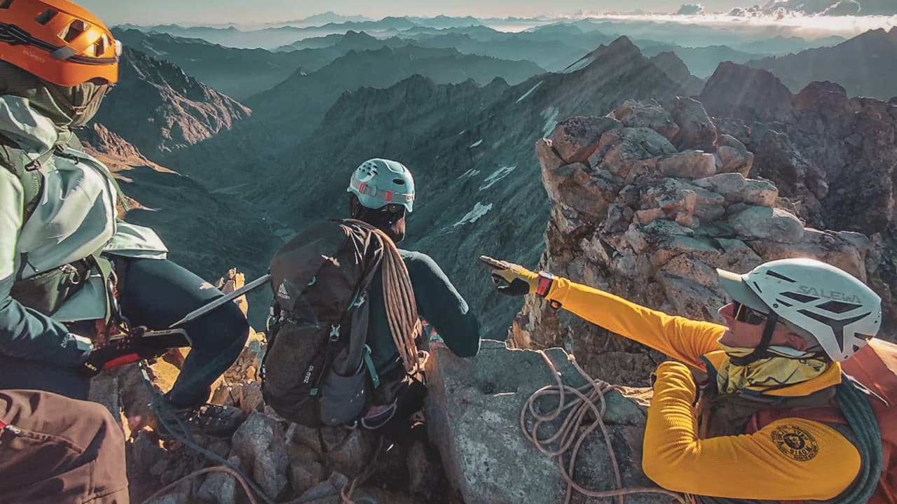 Trois alpinistes sur un sommet, admirant des paysages montagneux à couper le souffle dans les Écrins.