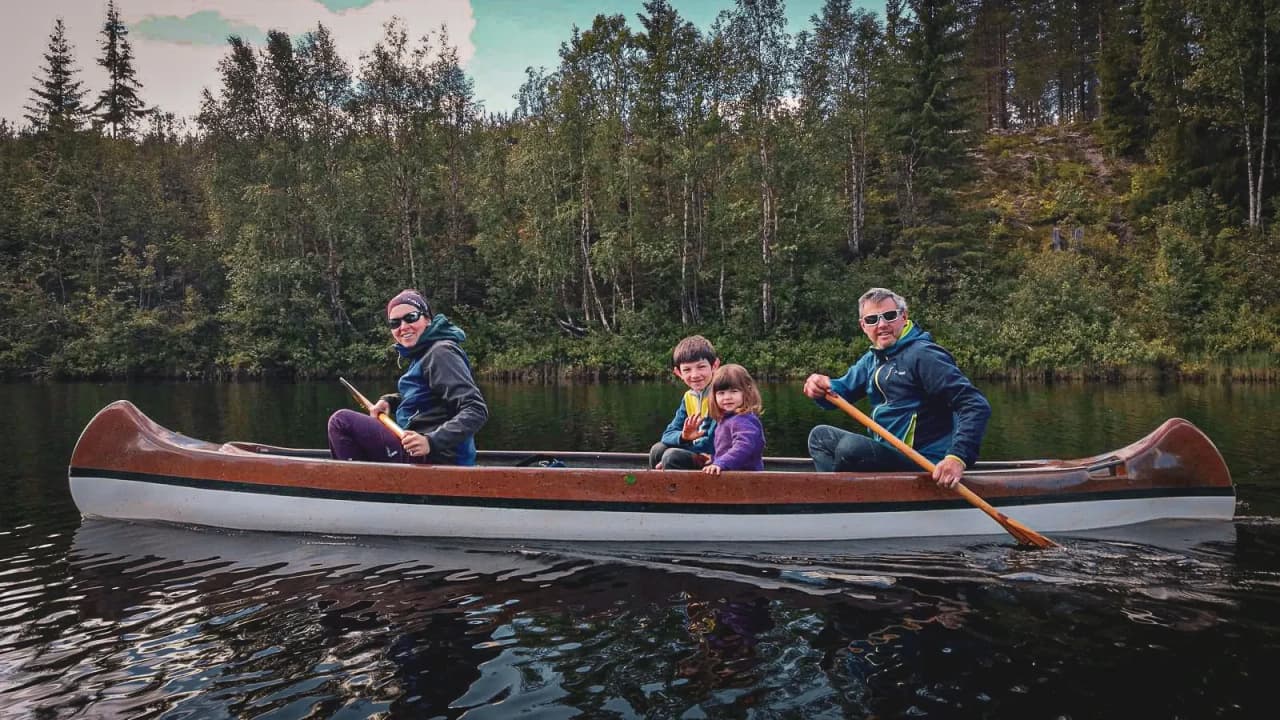Vier lachende avonturiers peddelden in een kano midden in een vredig Zweeds bos.