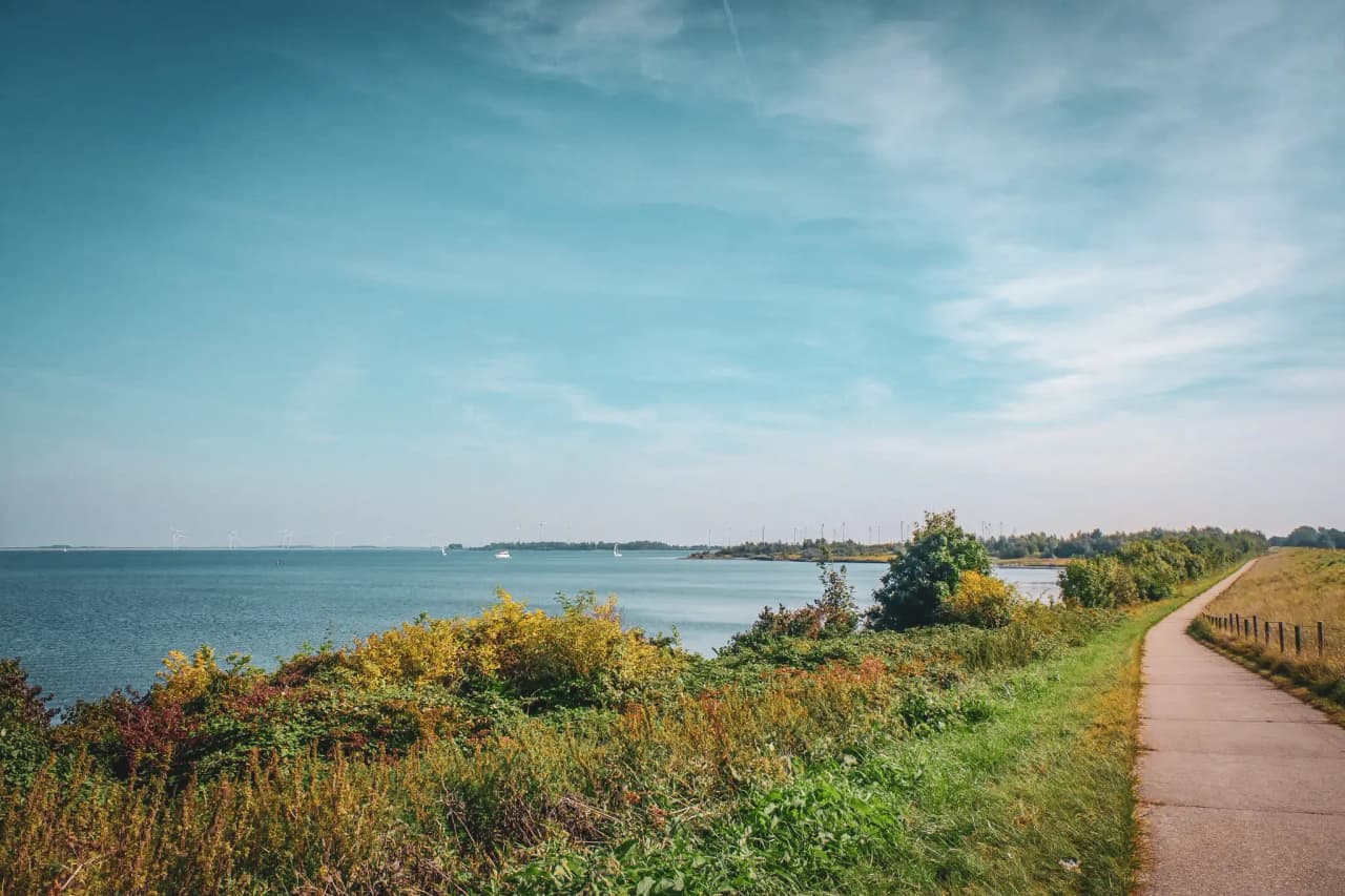 A serene Zeeland coastline, lush green paths, calm seas and brilliant blue skies. Perfect for adventure!