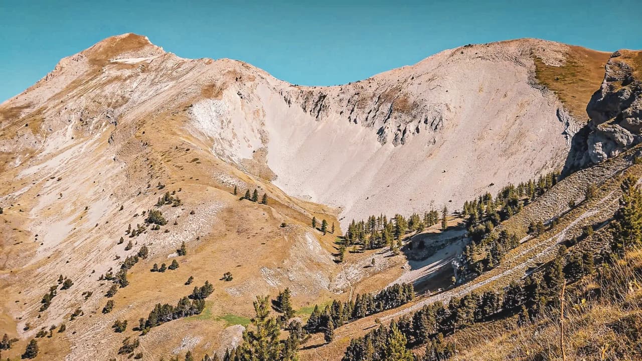 Een majestueus panorama van de heuvels van Dévoluy, waar bergweiden en bergkammen samenkomen onder een azuurblauwe hemel.