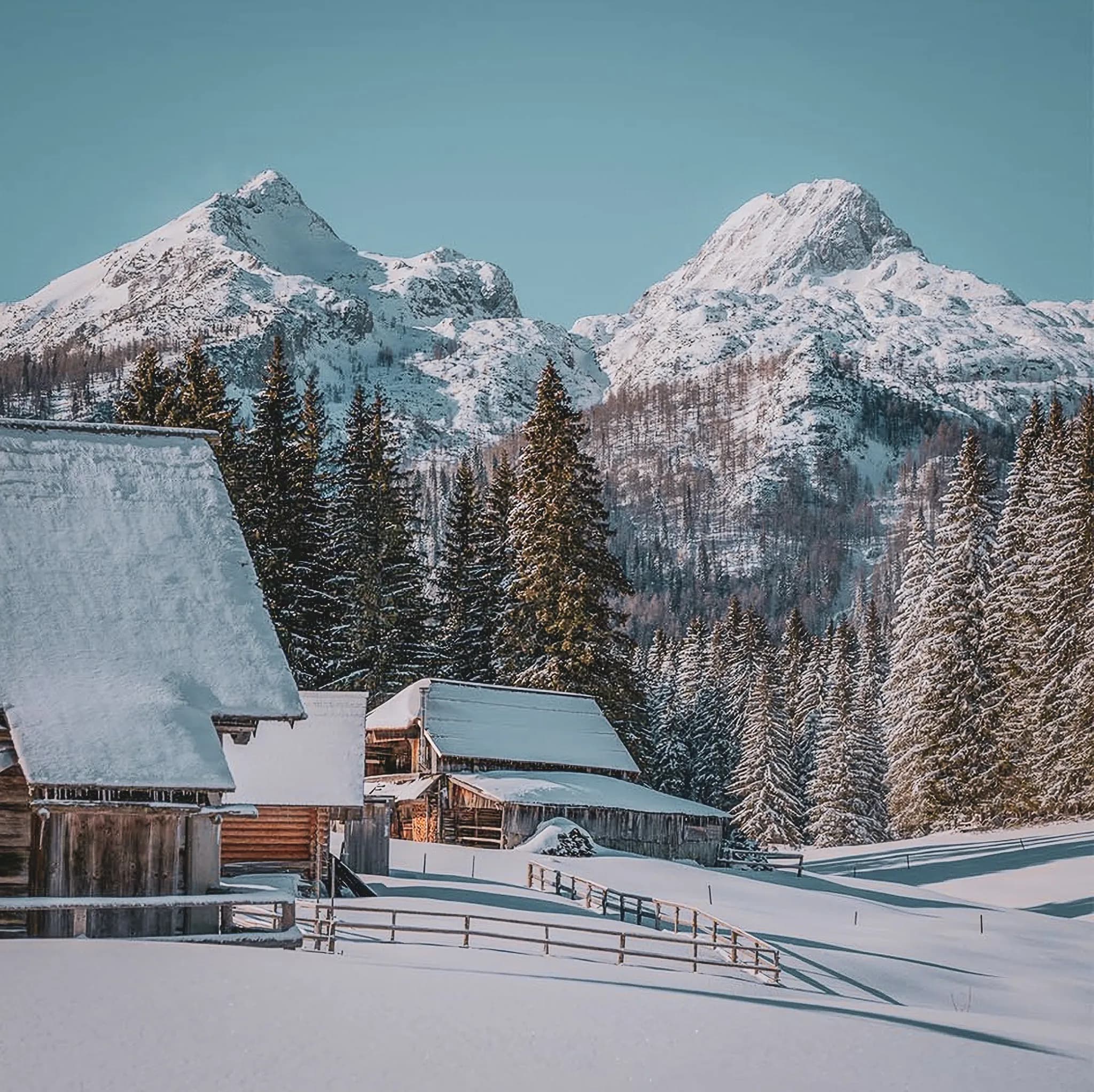 Paysage hivernal enchanteur des Alpes juliennes en Slovénie, avec montagnes majestueuses et chalets pittoresques.