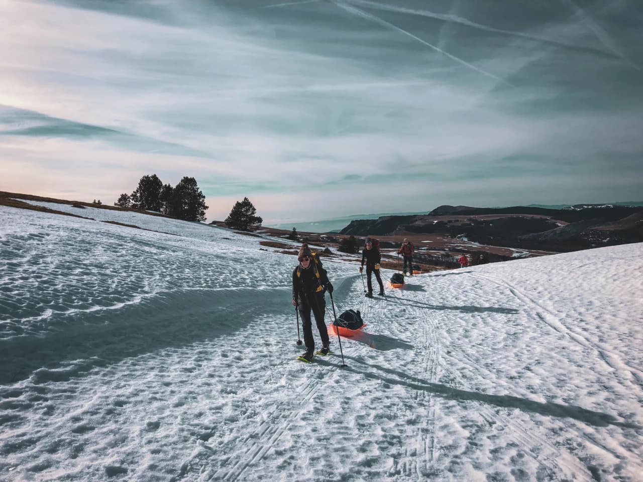 Group of adventurers on snowshoes crossing a snowy landscape, with mountains in the background.