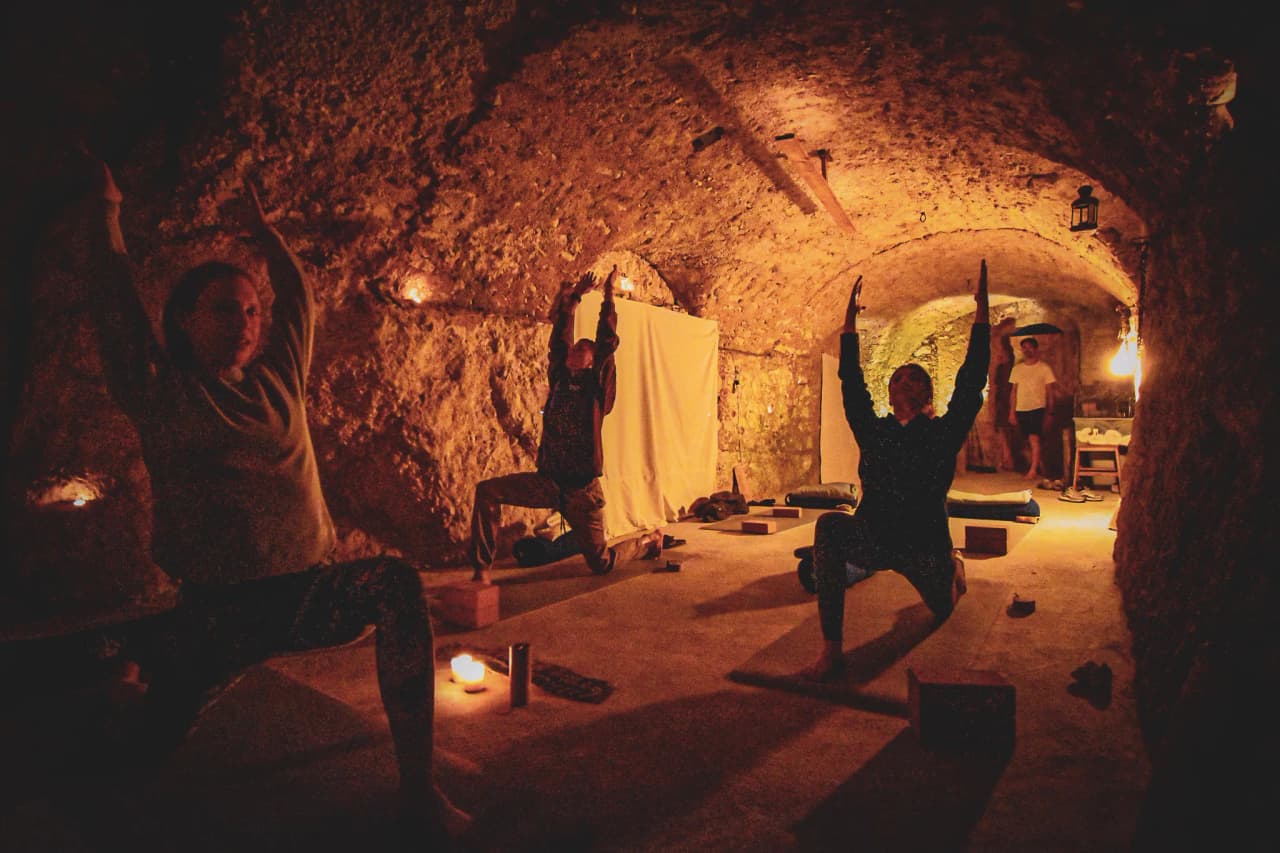 Deelnemers oefenen yoga in de warme, rustgevende sfeer van een Italiaanse kelder.