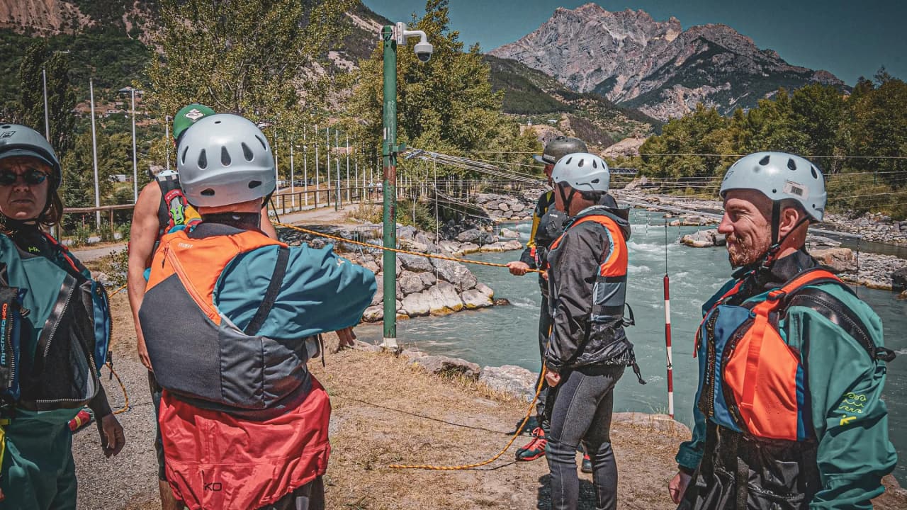 Een groep packrafters die klaar zijn om kennis te maken met de rivier, met berglandschappen op de achtergrond.