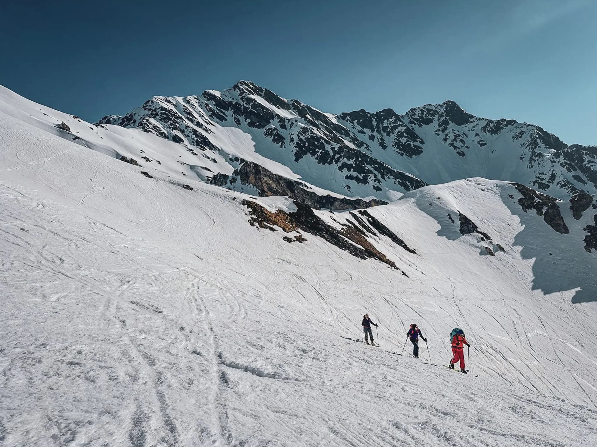 A group of skiers on an alpine slope, surrounded by majestic snow-capped peaks.