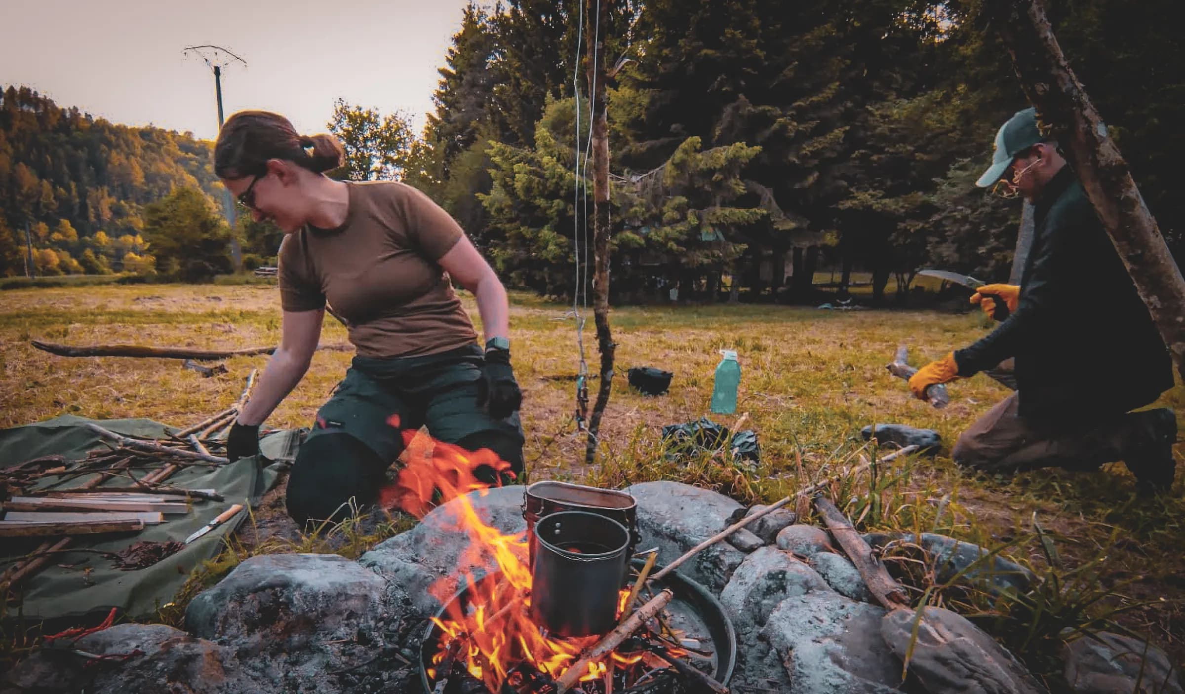 Een knapperend kampvuur, mensen midden in overlevingsactiviteiten in het bos, een natuurlijke sfeer.