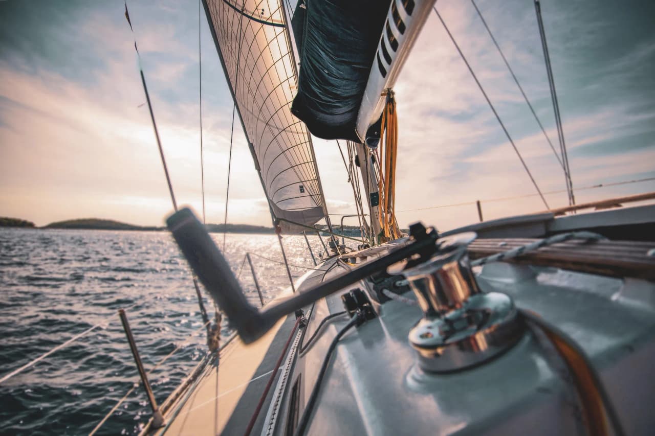 Voilier naviguant sur des eaux scintillantes, ciel lumineux et paysages marins enchanteurs.