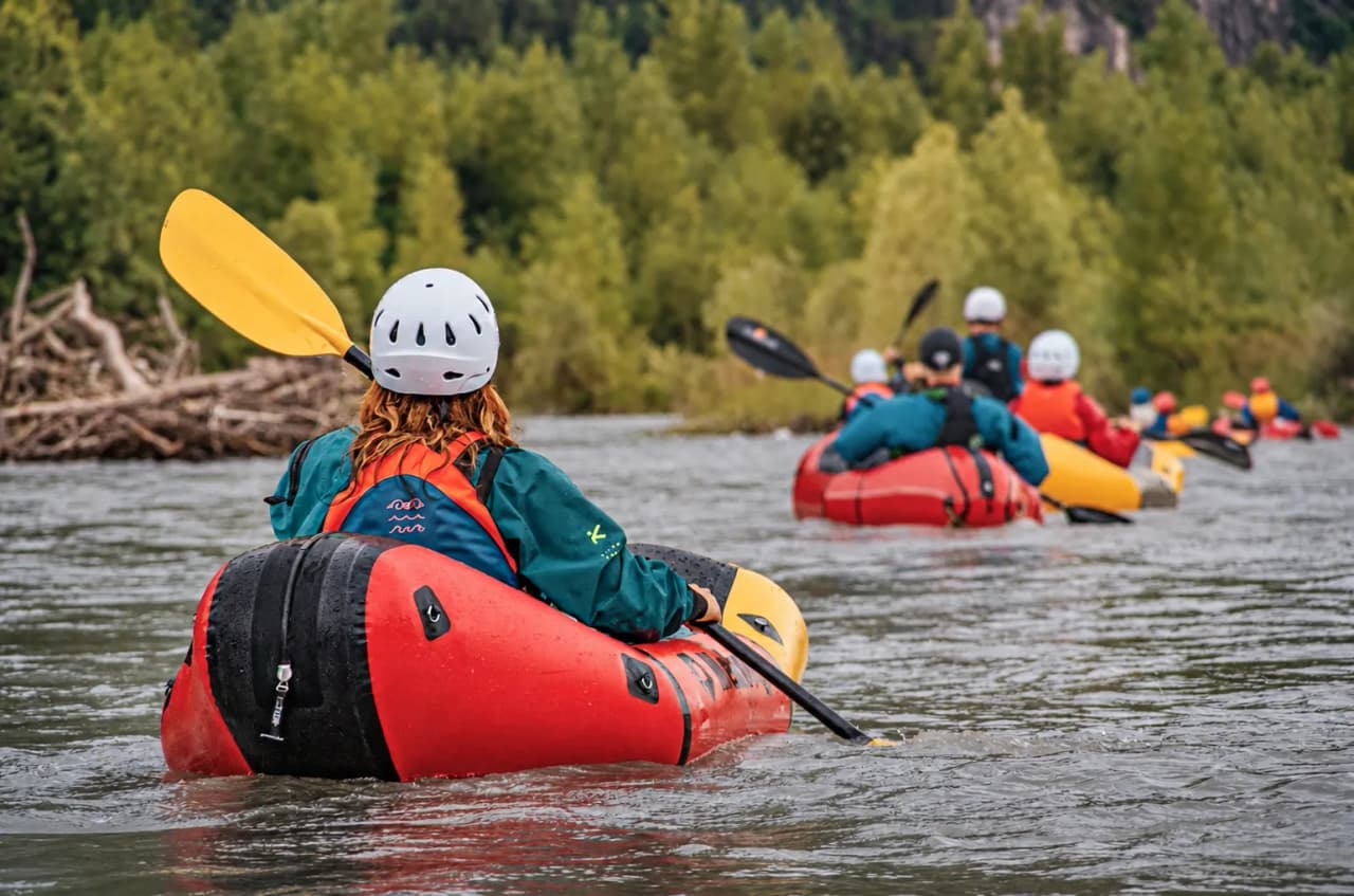 Een groep packrafters op een rivier te midden van het groen, op zoek naar avontuur in de Alpen.