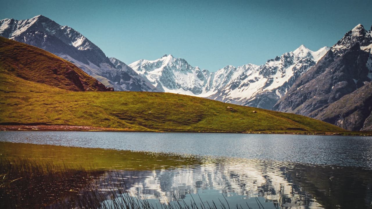 Lacs turquoise entourés de montagnes majestueuses sous un ciel azur, invitation à l'aventure.