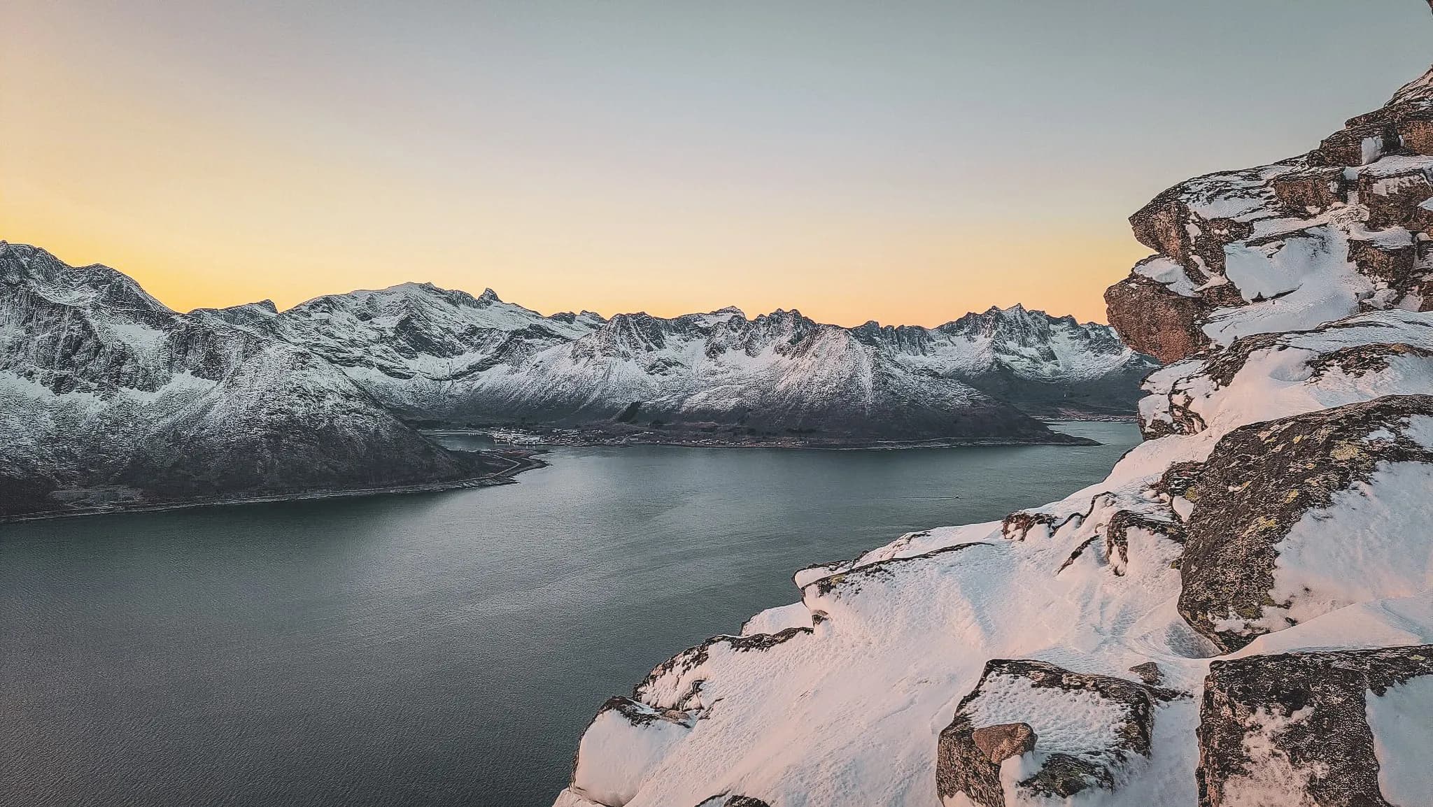 Majestic view of snow-capped mountains overlooking a sparkling fjord in Senja, Norway.