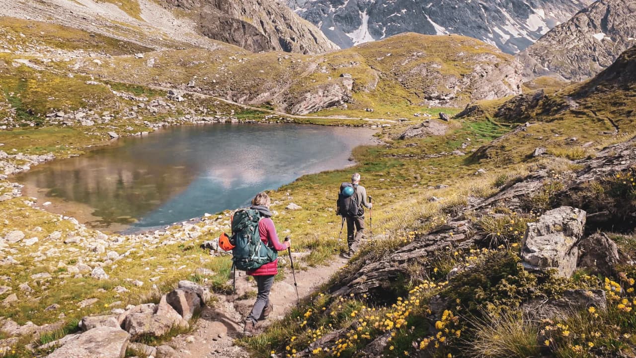 Hikers on their way to an Alpine lake, surrounded by majestic Alpine scenery.