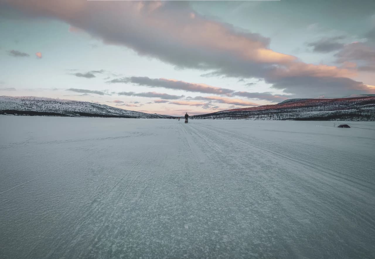 An adventurer on a pristine glacier, under a pastel sky, invites you to explore wild Lapland.