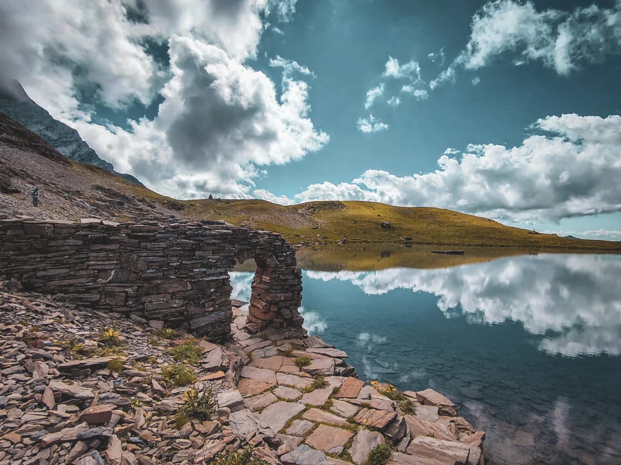 Reflecting the sky on a peaceful alpine lake, surrounded by breathtaking mountain scenery.
