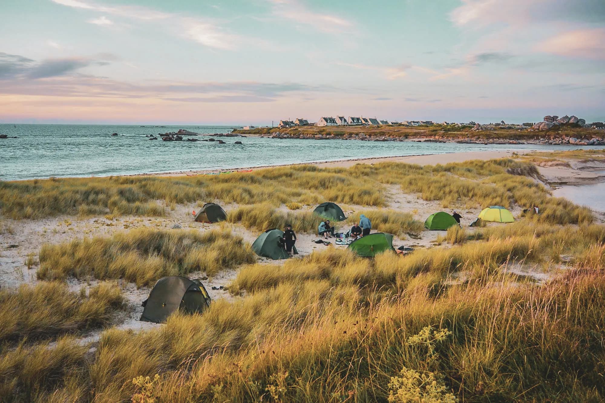 Tents by the sea, surrounded by lush green dunes, for a tranquil adventure.