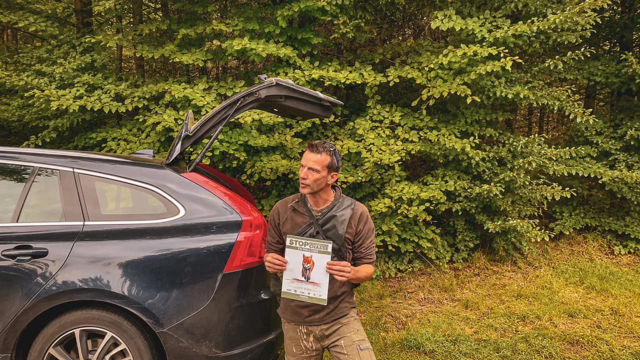 Un guide passionné présente une brochure sur le brame du cerf, au cœur de la forêt verdoyante.