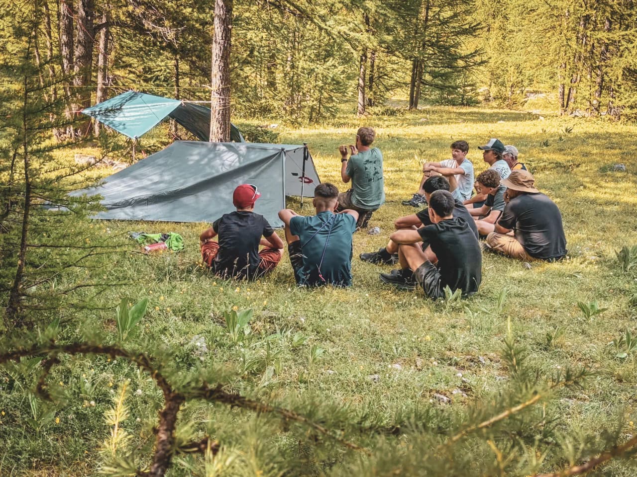 Groupe de jeunes en pleine nature, échangeant des techniques de survie au cœur des Alpes.