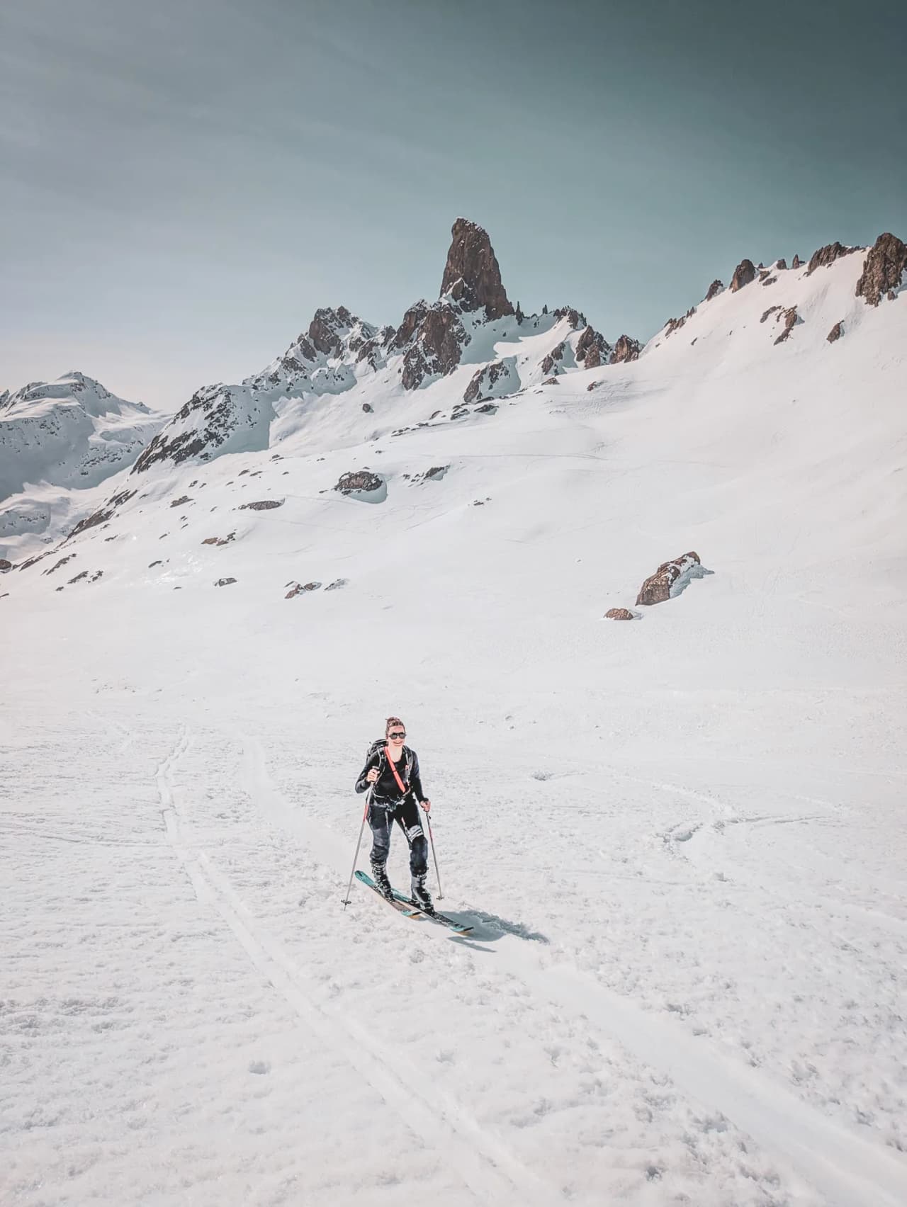 Ski touring in a majestic alpine landscape, with snow-capped peaks and a blue sky.