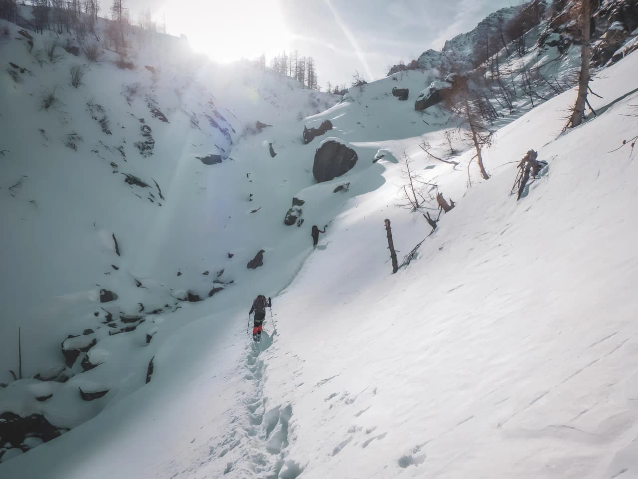 Un sentier enneigé dans les Alpes italiennes, avec des randonneurs découvrant la cascade de glace.