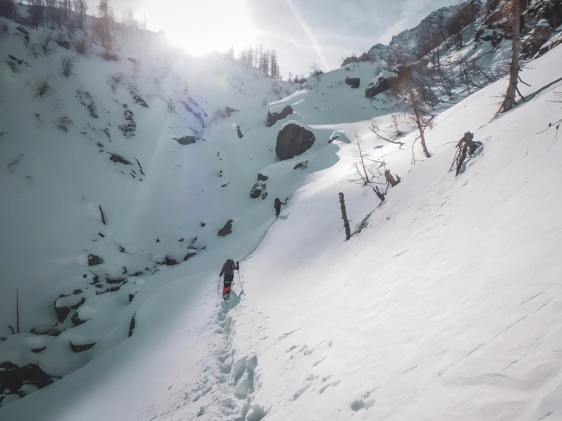 Un sentier enneigé dans les Alpes italiennes, avec des randonneurs découvrant la cascade de glace.