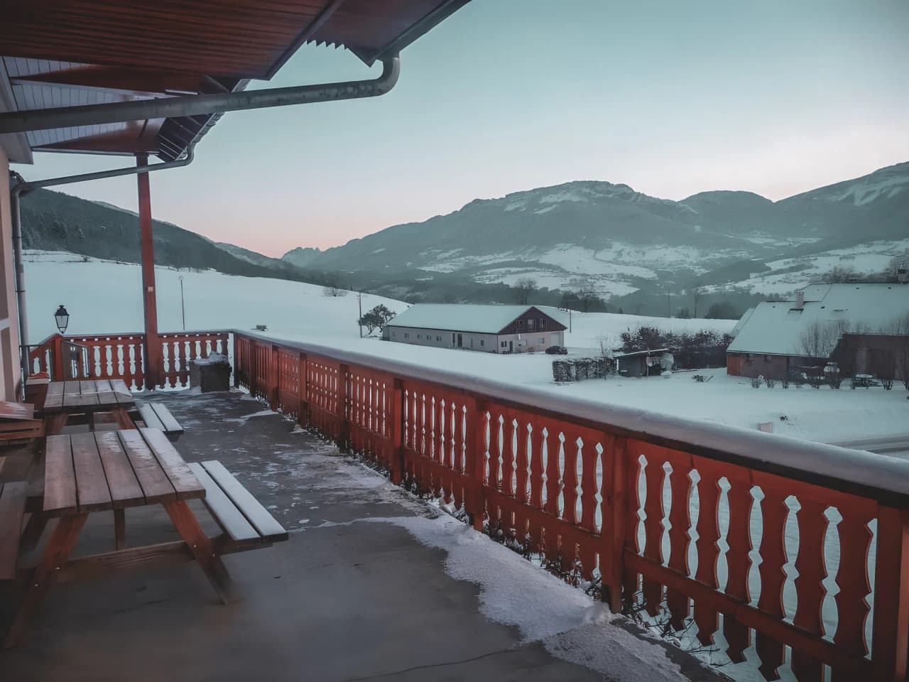 Balcon chaleureux avec vue sur montagnes enneigées, invitant à la randonnée en plein air.