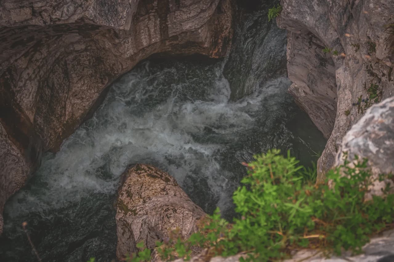 Aerial view of the tumultuous waters of an alpine river surrounded by rocky cliffs in Slovenia.