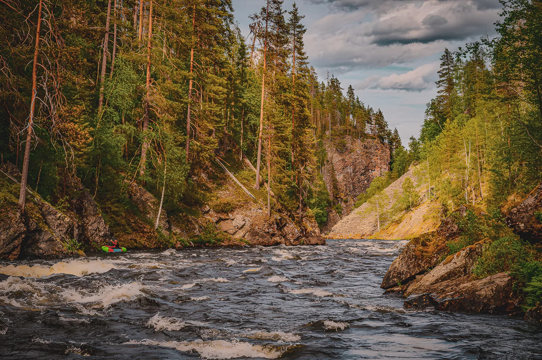 Rushing rivers and lush forests, a wild Lapland landscape to explore by packraft.