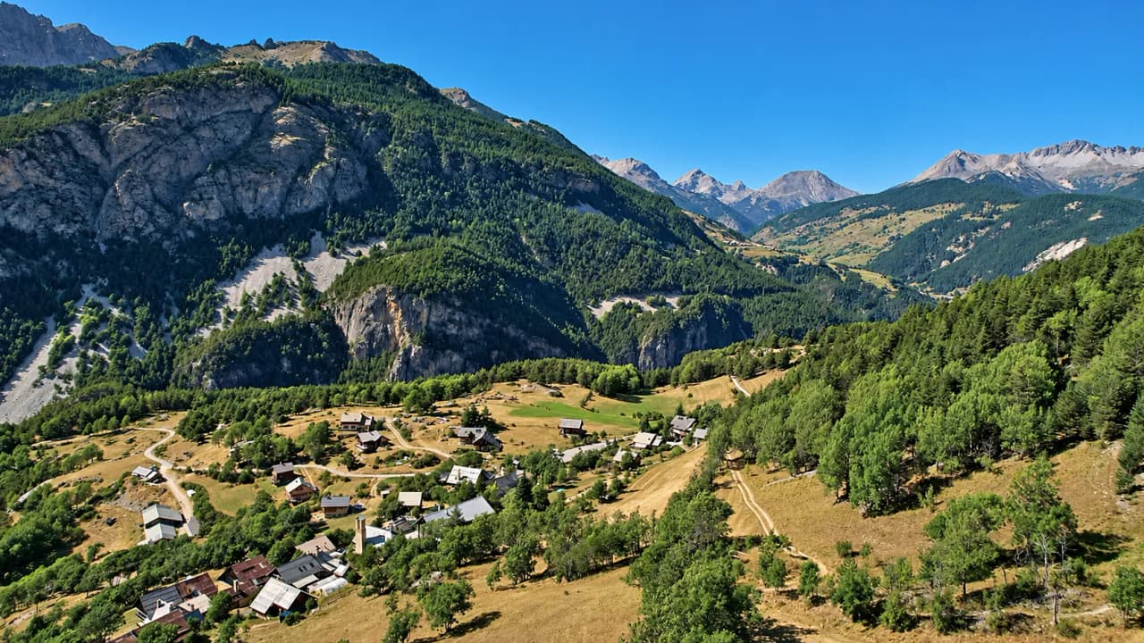 Panoramisch uitzicht op het Queyras-gebergte, een schilderachtig dorpje omgeven door groen.