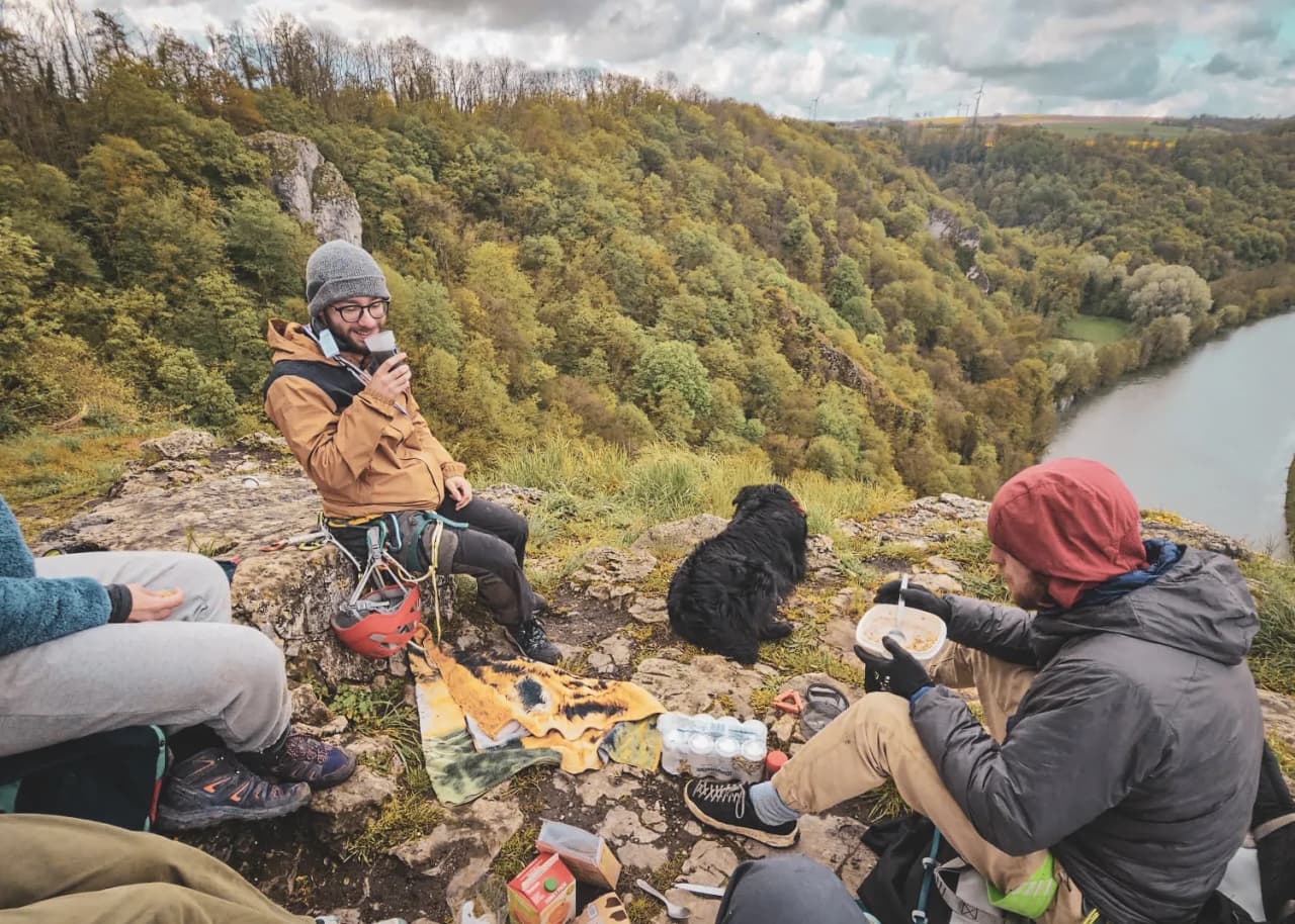 amis profitant d'un pique-nique avec vue plongeante sur la vallée verdoyante.