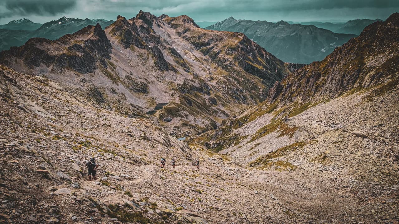Vue panoramique des montagnes du Beaufortain, avec des randonneurs sur un sentier escarpé.