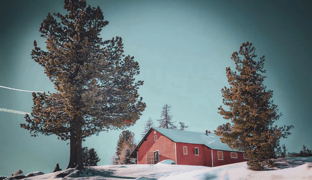 A picturesque Mountain hut in the snow, surrounded by majestic trees, in the heart of the Alps between France and Italy.