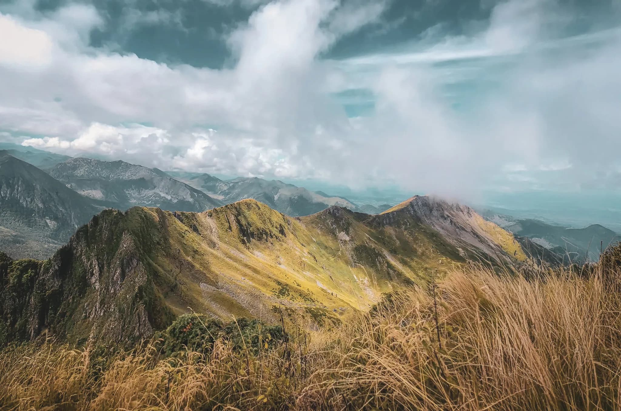 Paysage majestueux des Pyrénées, avec des montagnes verdoyantes sous un ciel nuageux.
