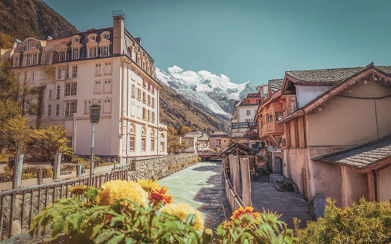 Vue panoramique de la vallée de Chamonix, entre bâtiments pittoresques et sommets enneigés.
