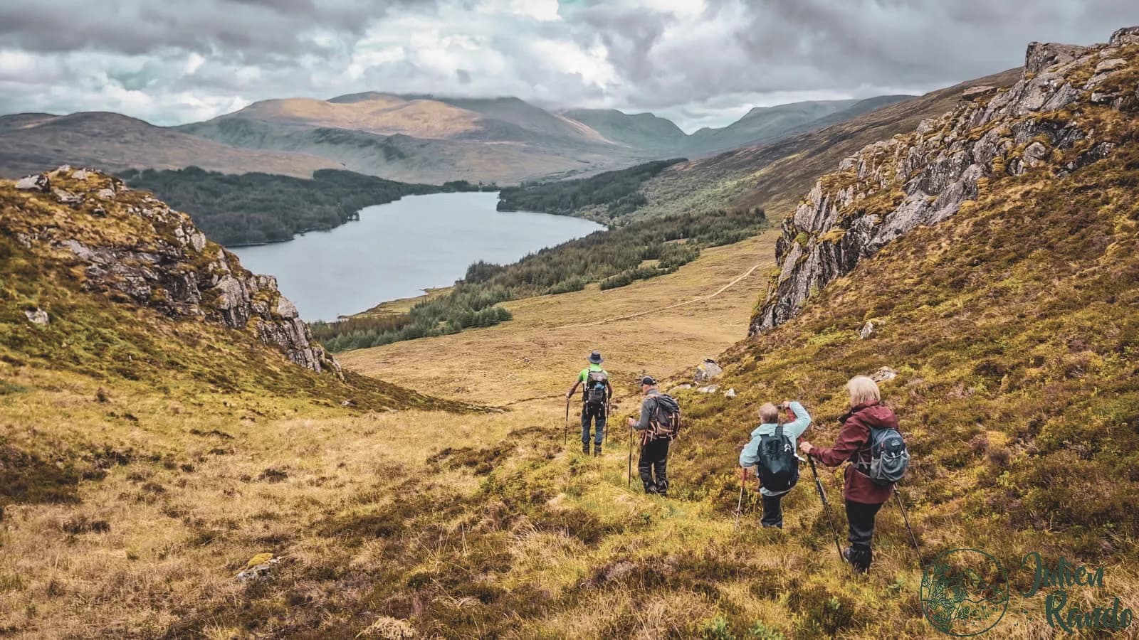 A walk in the Scottish Highlands, with hikers descending towards a majestic loch.