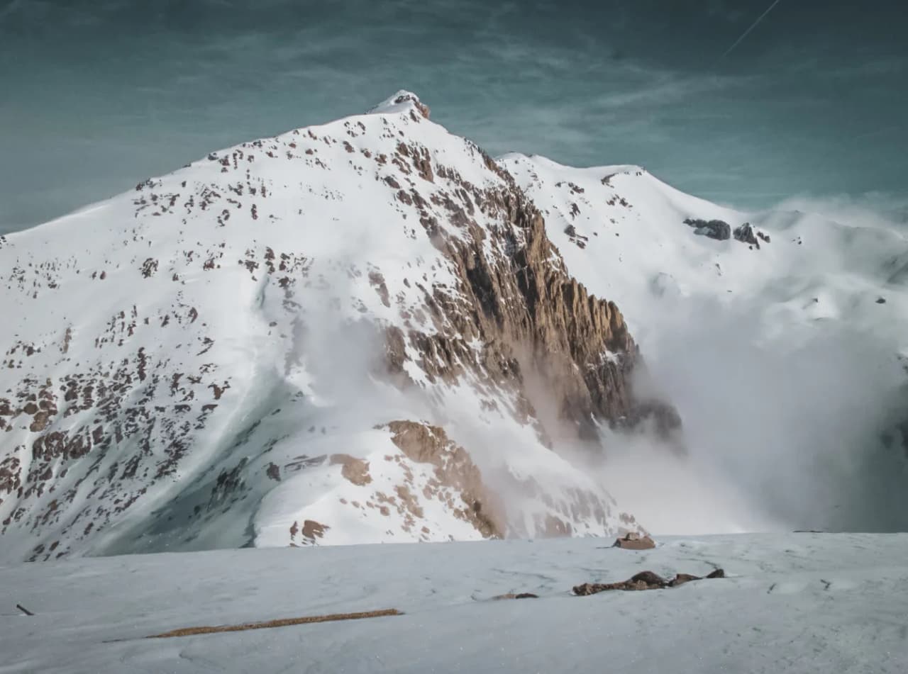 Majestic snow-capped mountains, caressing mist, an invitation to alpine adventure.