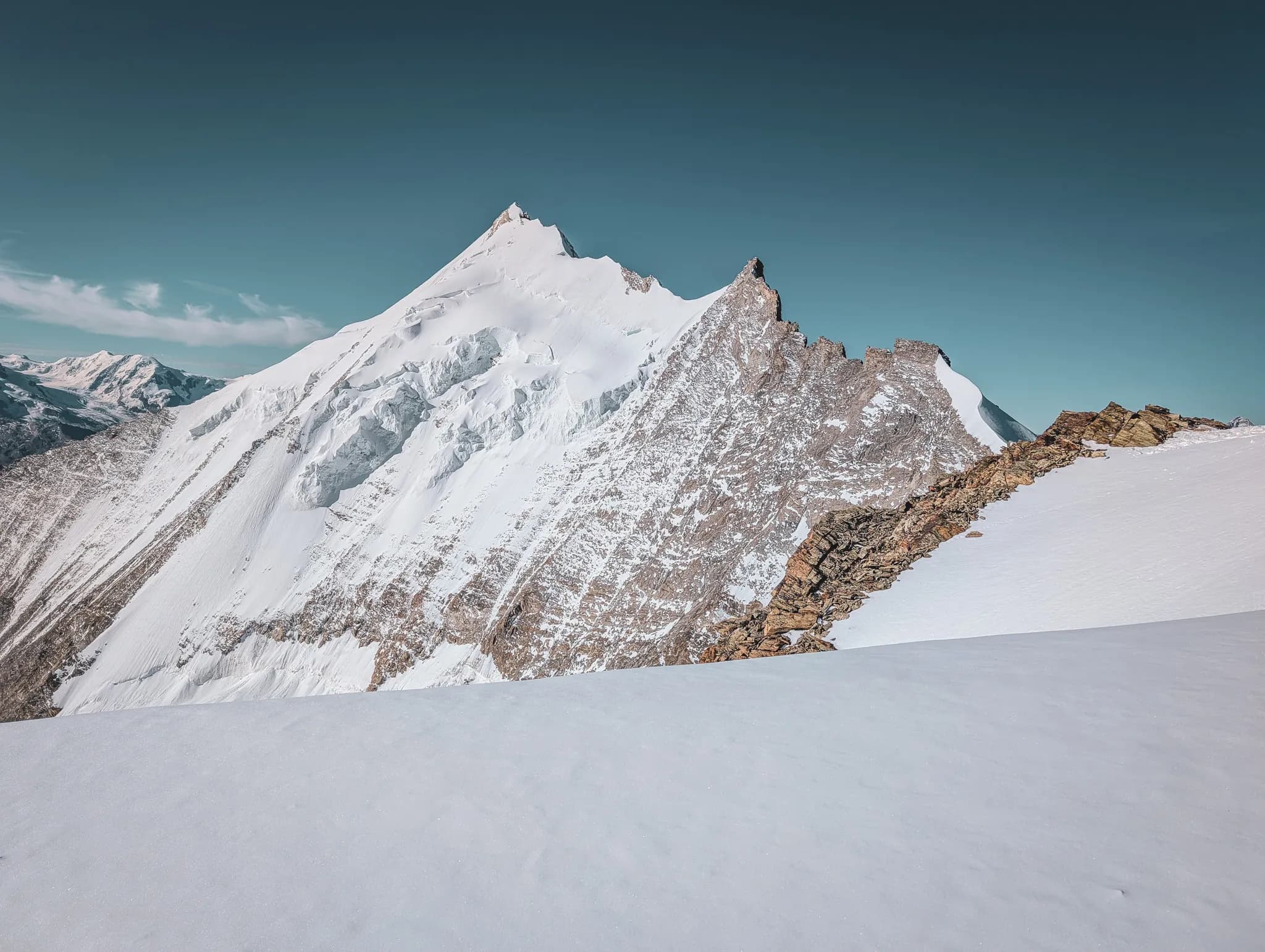 A captivating Alpine panorama with snow-capped peaks and white flowers in the foreground.