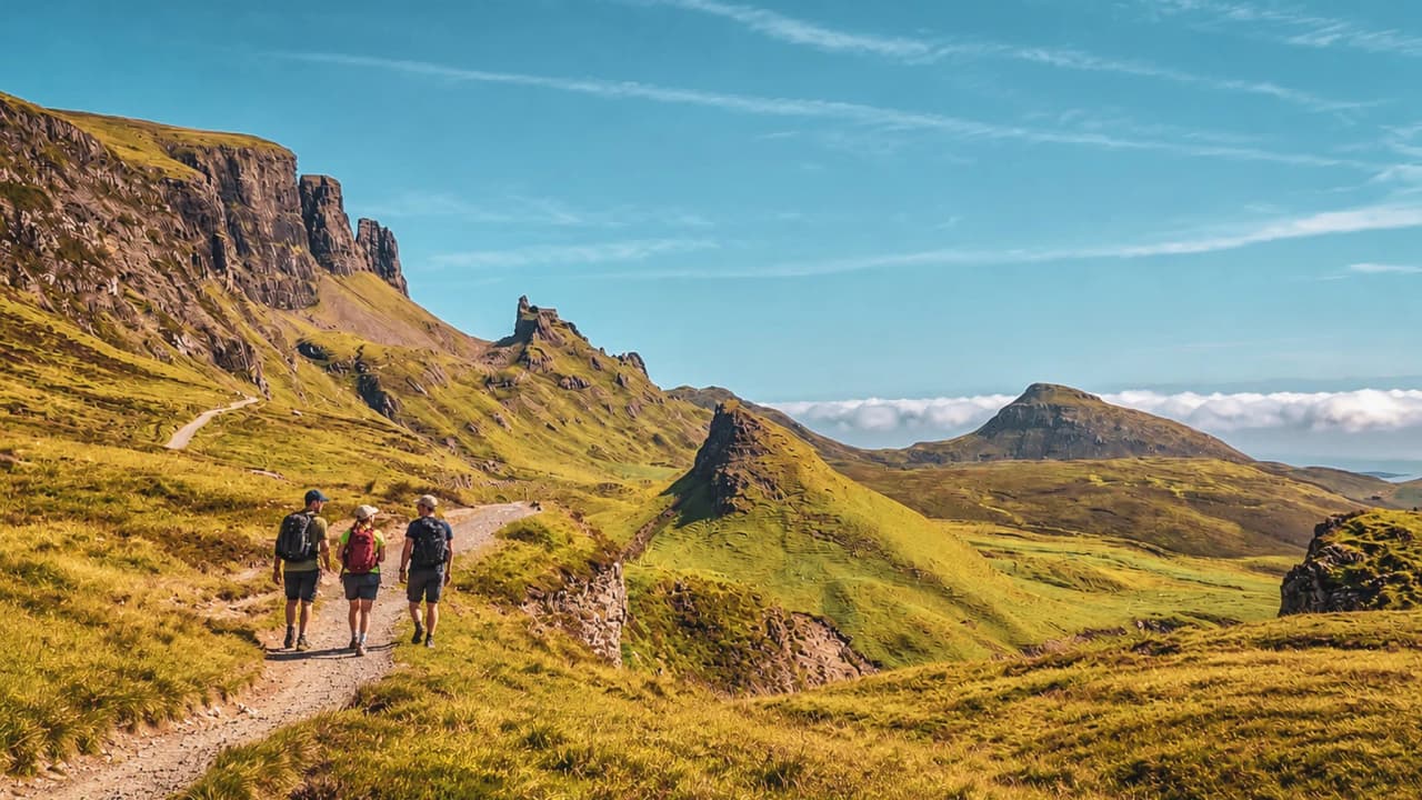 Drie wandelaars genieten onder een strakblauwe hemel van de betoverende landschappen van het eiland Skye.