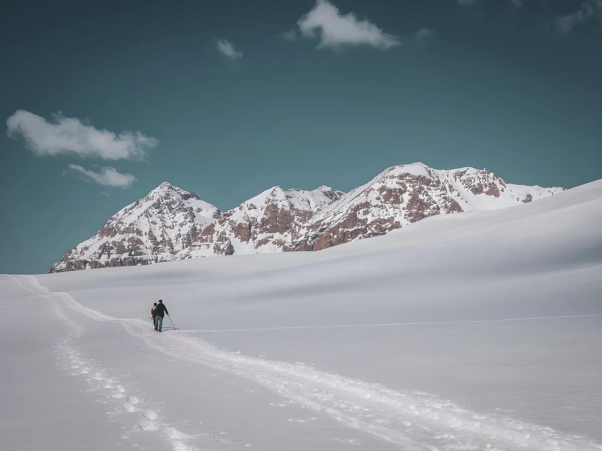 Snowshoe trekking in a snow-covered alpine landscape, majestic mountains in the distance.