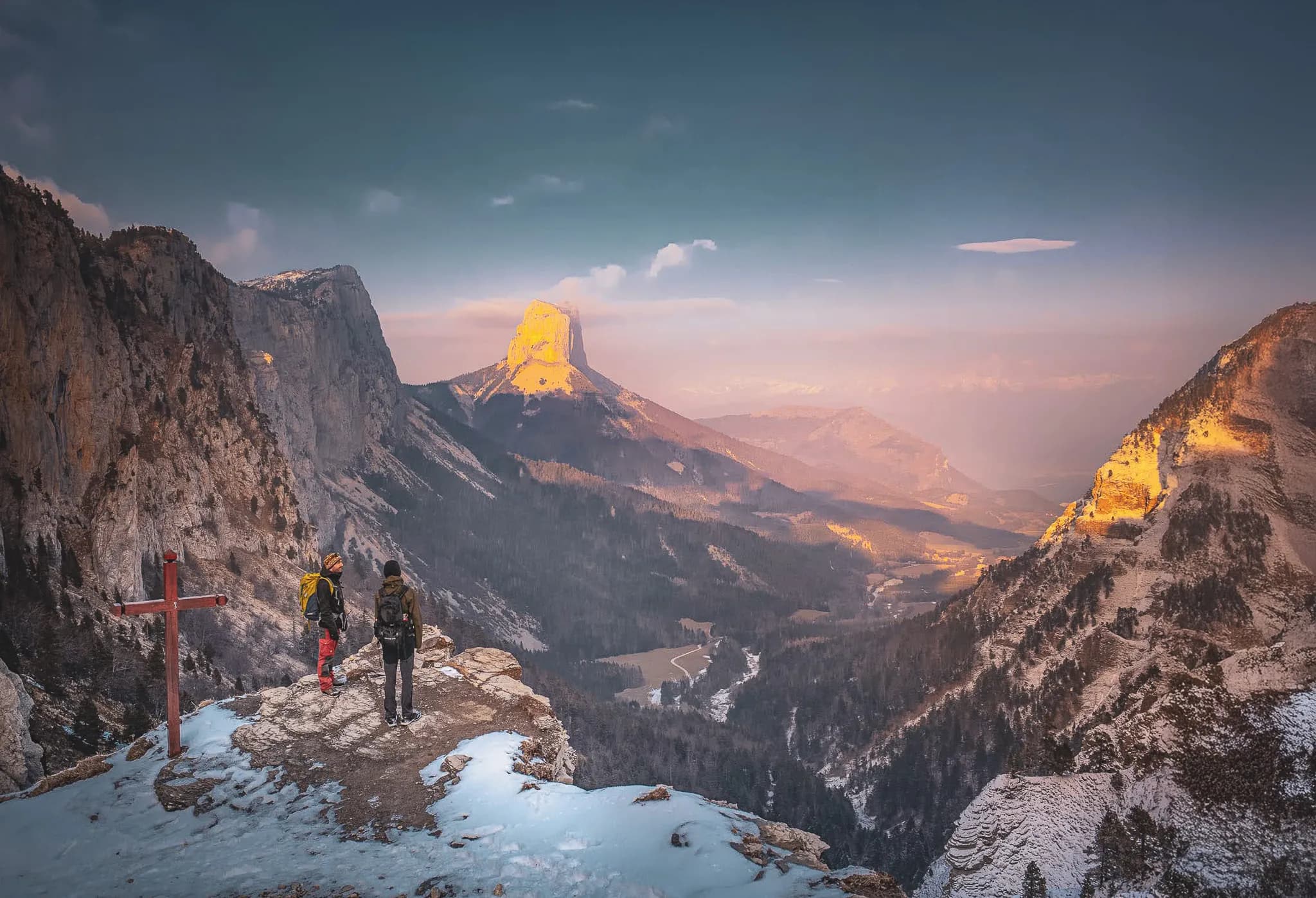 Two hikers admire an enchanting mountain landscape as the sun sets over the Vercors.